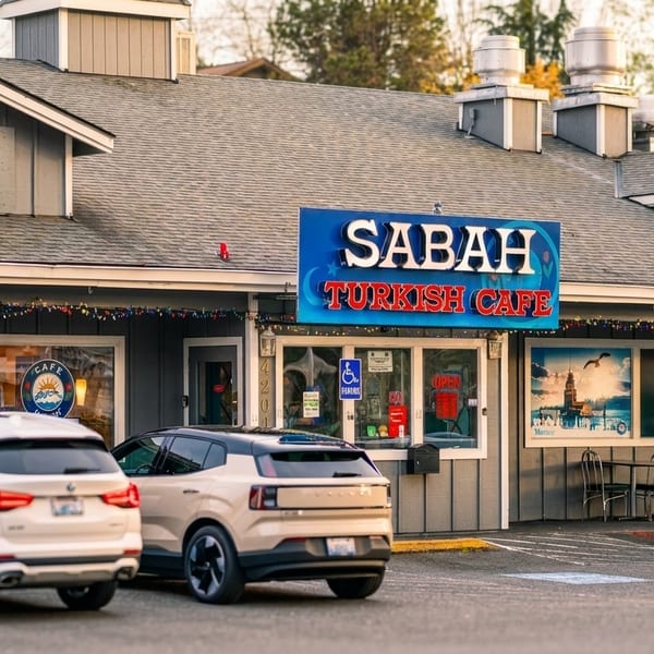 Exterior of Sabah Turkish Cafe with cars parked in front, American flags, and festive lights.