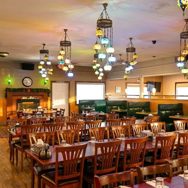 Spacious restaurant dining room with wooden tables, green booths, and colorful hanging lanterns.